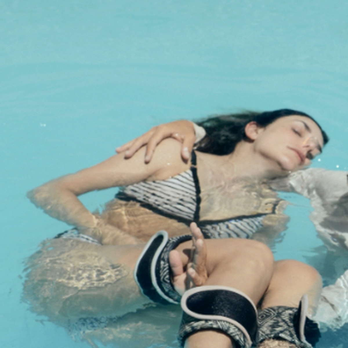 Woman resting deeply while held in bright turquoise water